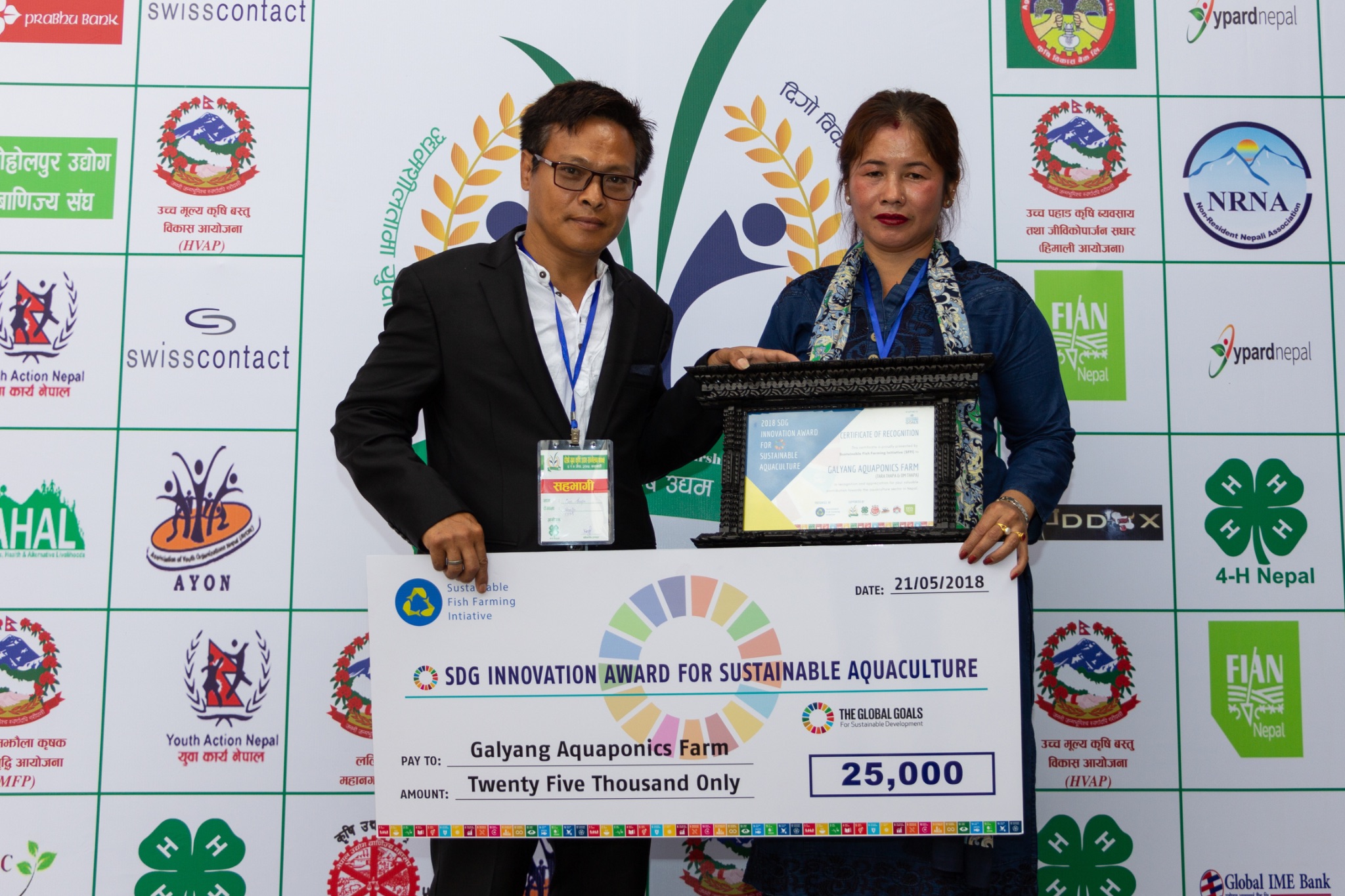 Om Thapa and Tara Thapa hold an SDG Innovation Award check and framed certificate for Galyang Aquaponics Farm.